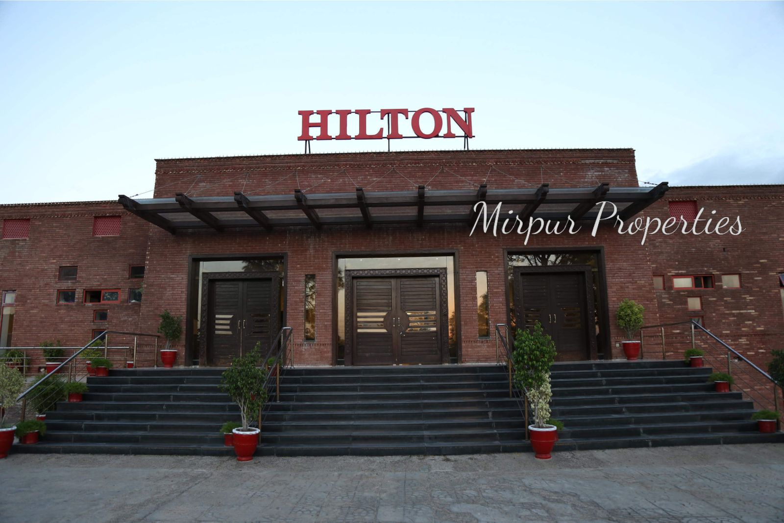 The front of a large brick building with a sign that says "Hilton" above the doors.