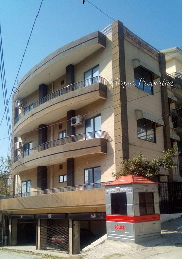 An apartment building with balconies and a car parked in front of it.