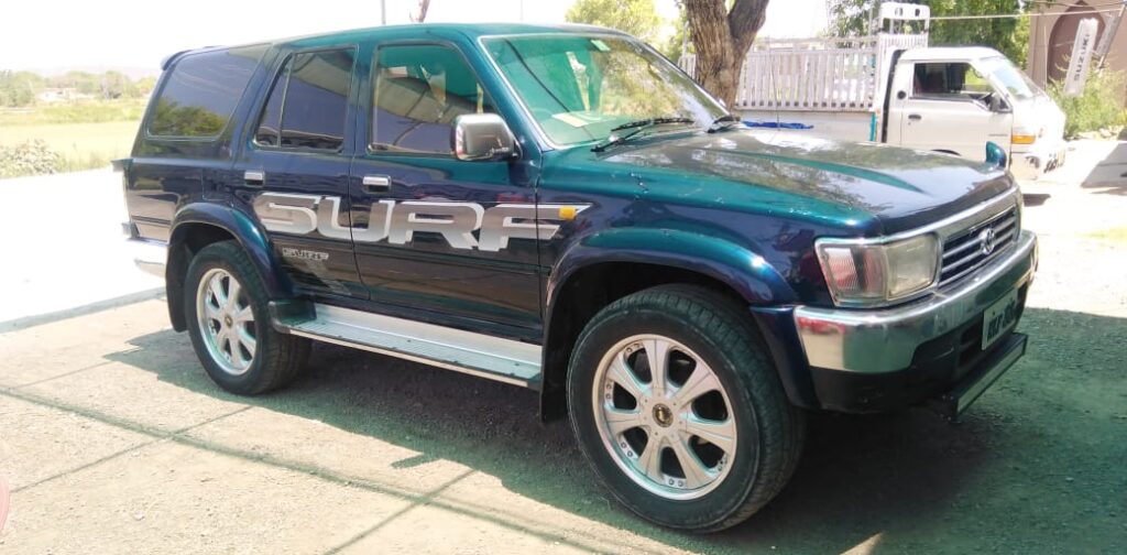 A dark green Toyota 4Runner SUV parked on a dirt road.