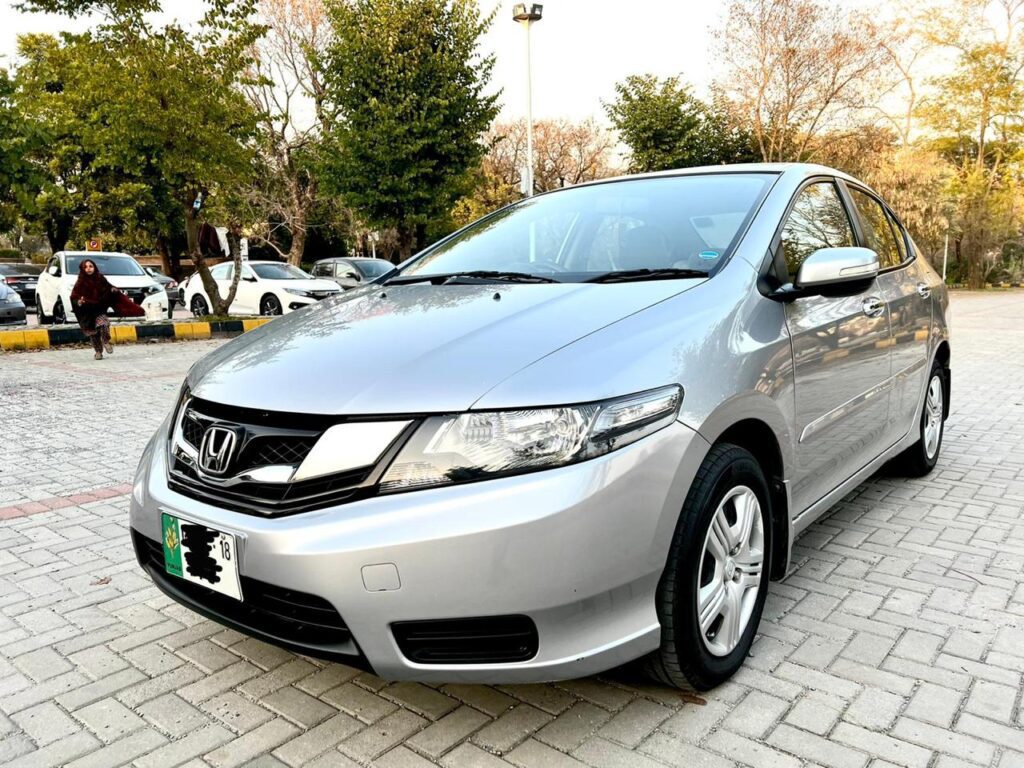 A silver Honda City car is parked on a brick driveway.