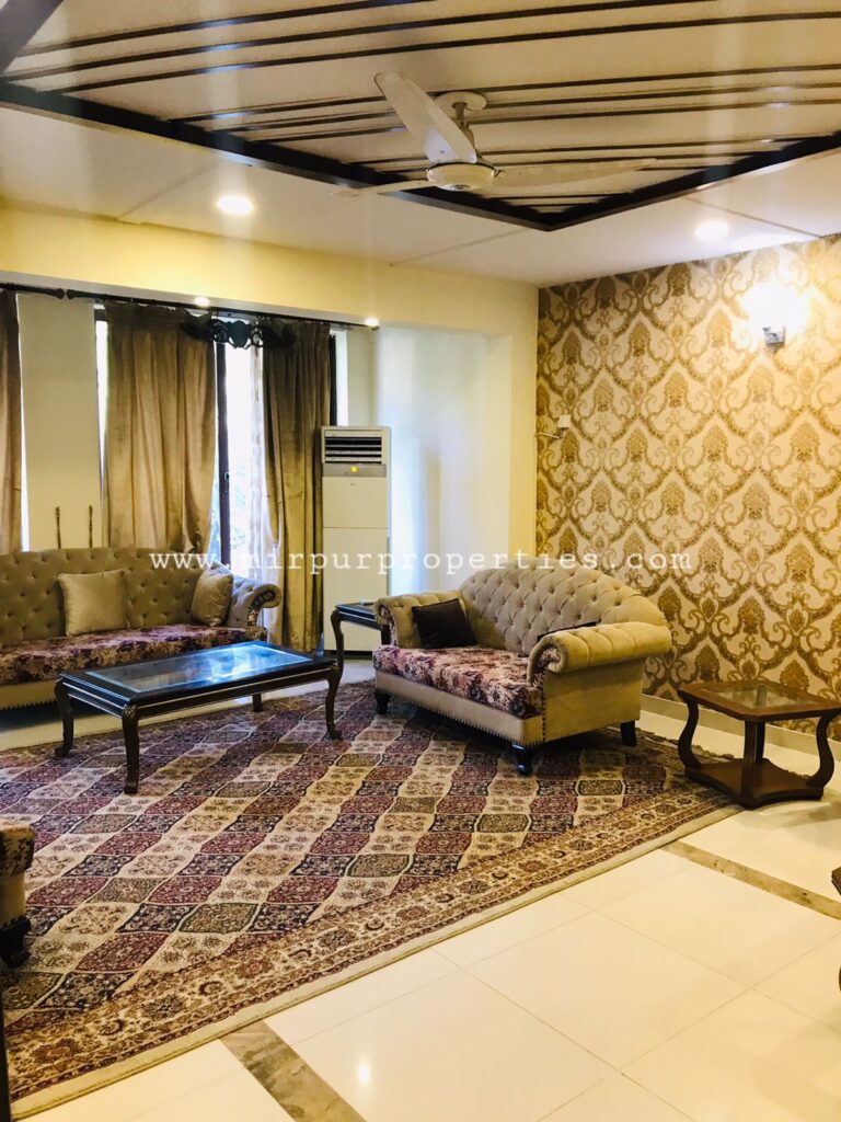 A cozy living room in Sector F-7 Islamabad with modern furniture and a ceiling fan.