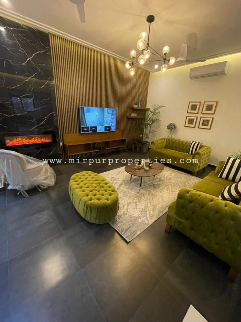 A living room with green couches and a fireplace, located in sector F-8 Islamabad Pakistan.