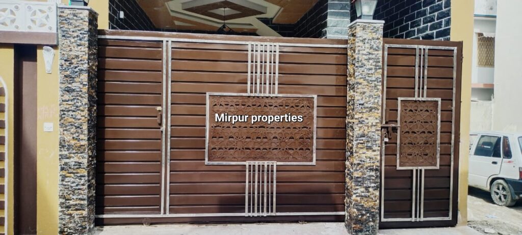 A brown gate with a sign advertising a house for sale in Abbottabad, Pakistan.