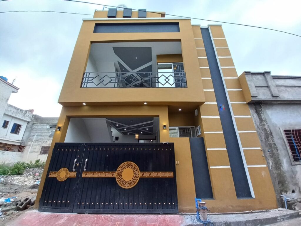 A yellow and black house with a black gate is located on Prince Road in Islamabad.