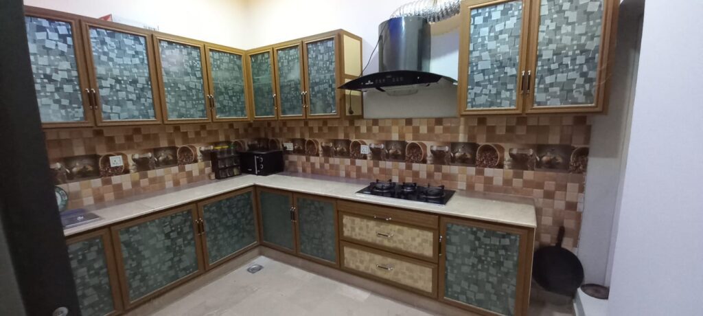 A kitchen with a stove and tiled walls located near Banigala in Islamabad.