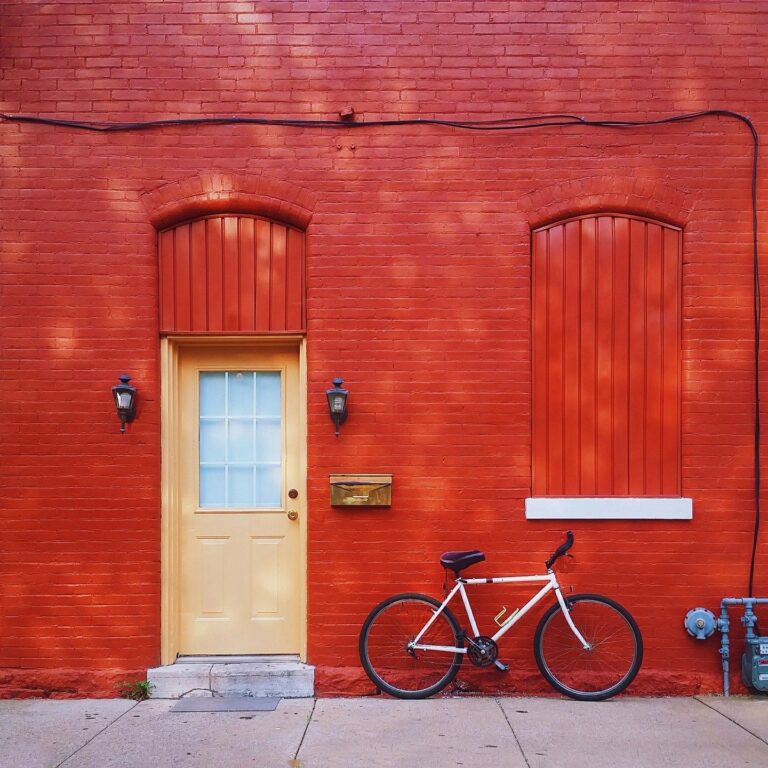 White bicycle parked in front of red brick building.