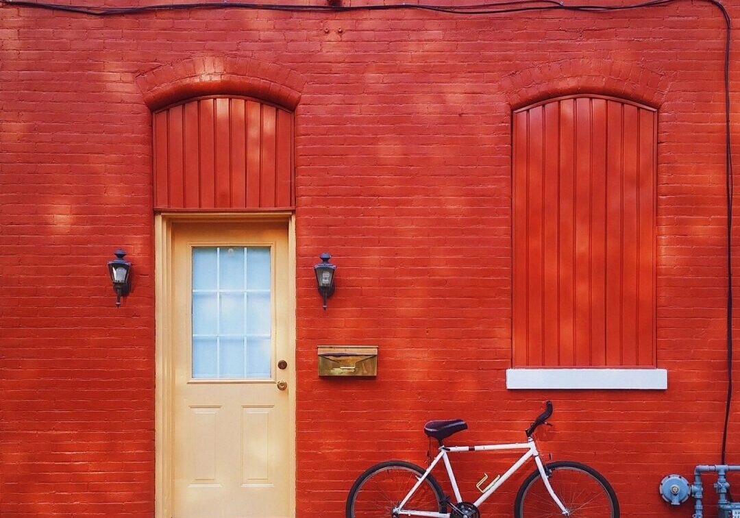 White bicycle parked in front of red brick building.